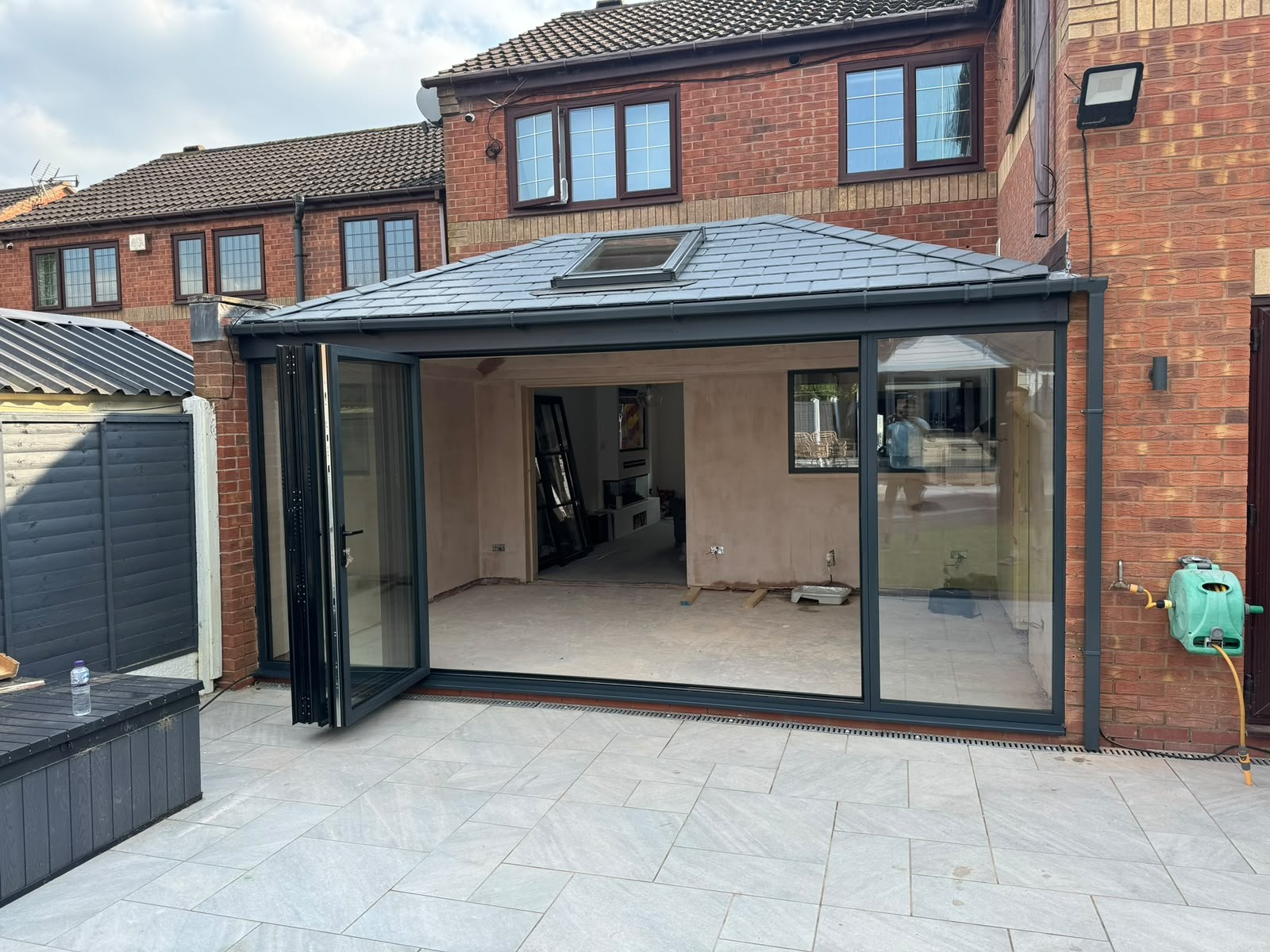 Grey aluminium bi-fold doors open onto a patio on a new rear extension