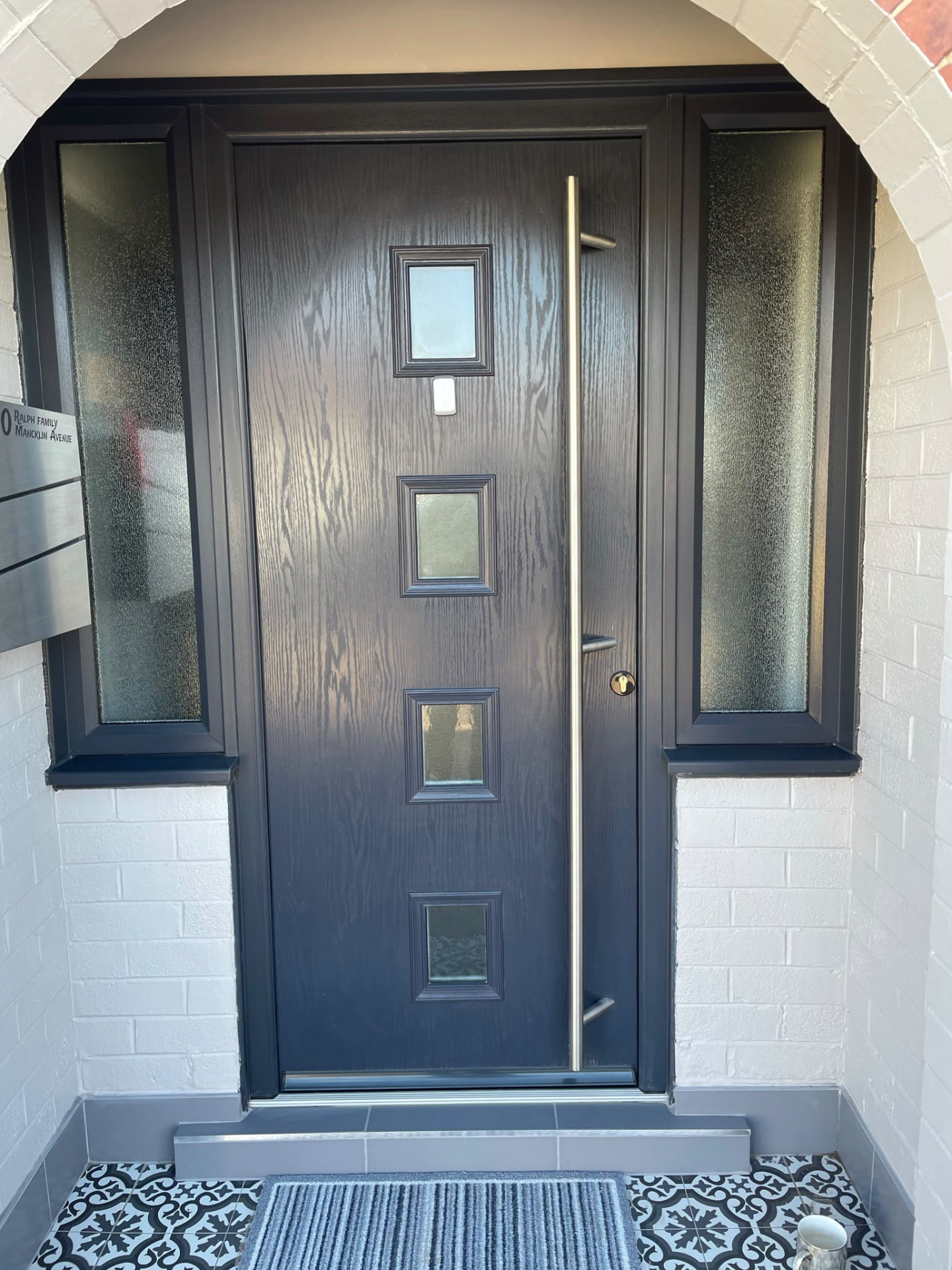 Grey composite front door with long bar handle and side glazing
