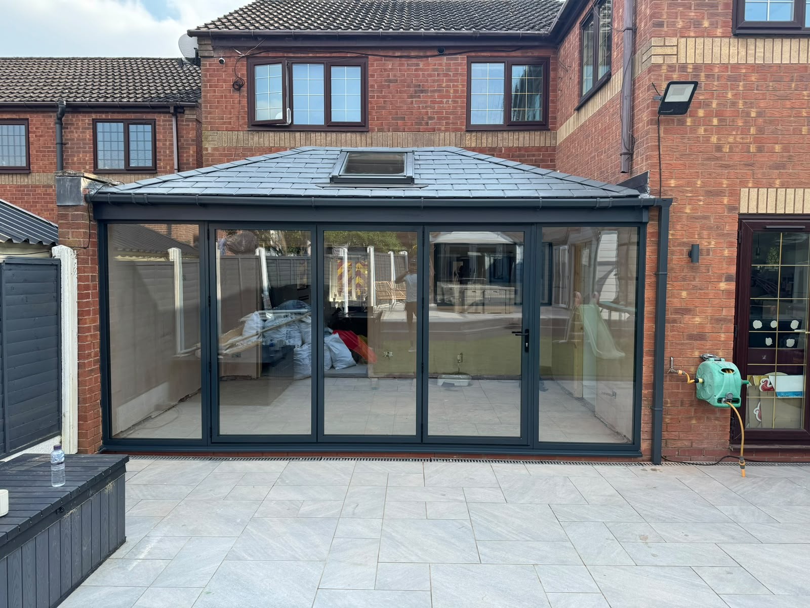 Grey aluminium bi-fold doors and glazed side panel on a tiled-roof extension