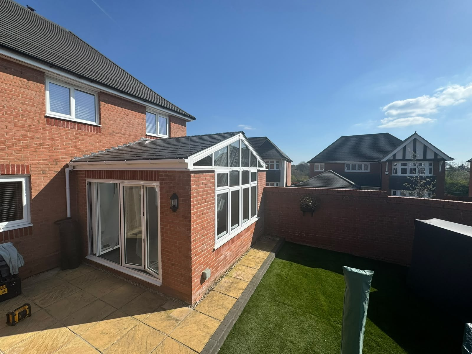 Completed brick rear extension with tiled warm roof, gable glazing and white patio doors
