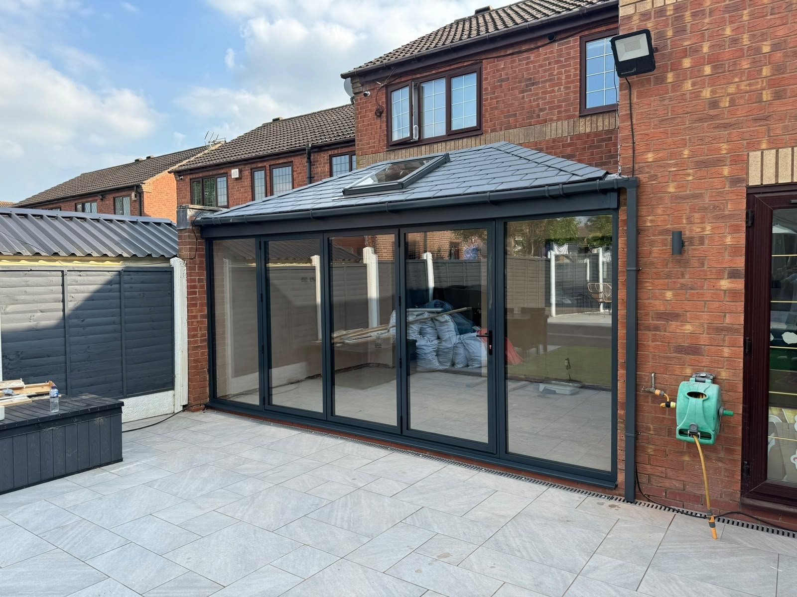 Grey aluminium bi-fold doors closed on a new tiled-roof rear extension