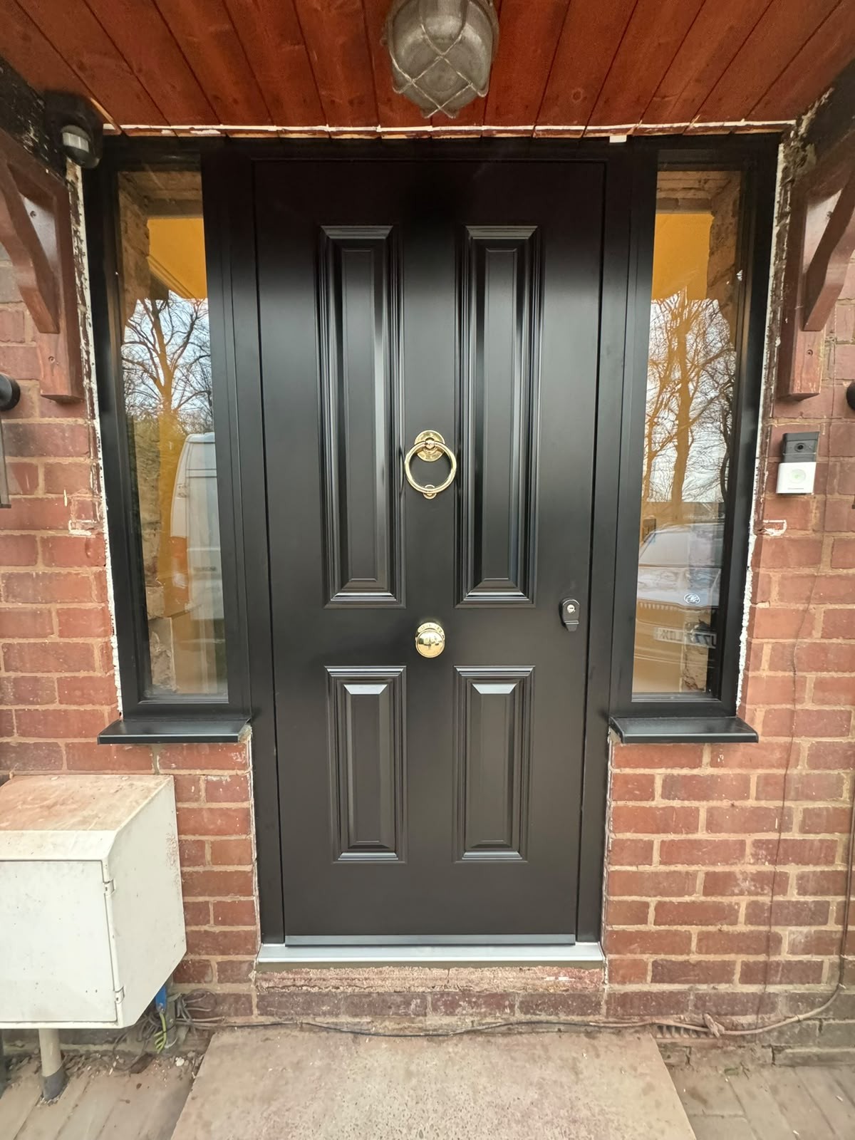 Black composite front door with polished brass knocker and handle