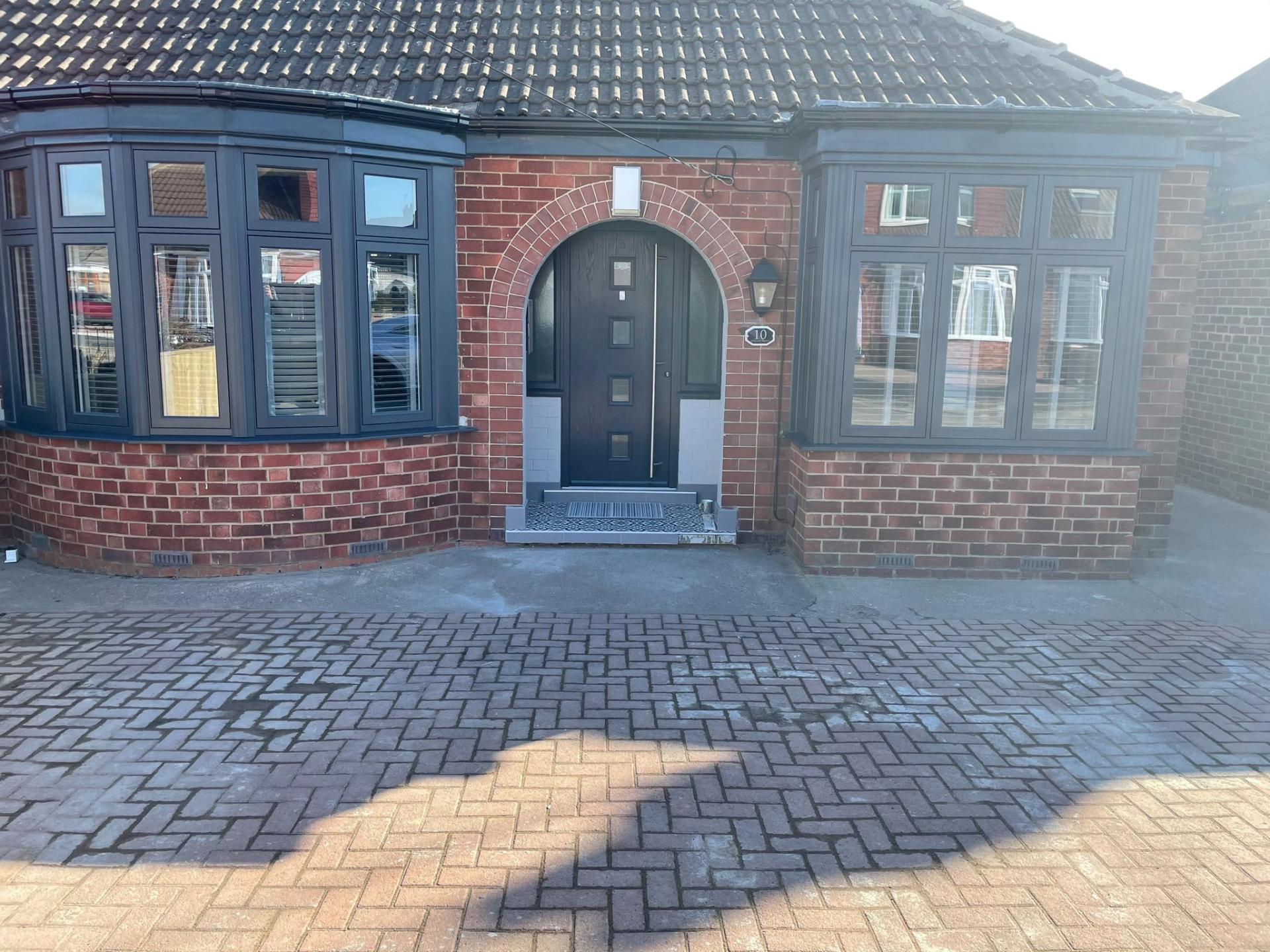 Full front elevation of a bungalow with new grey UPVC bay windows and composite door