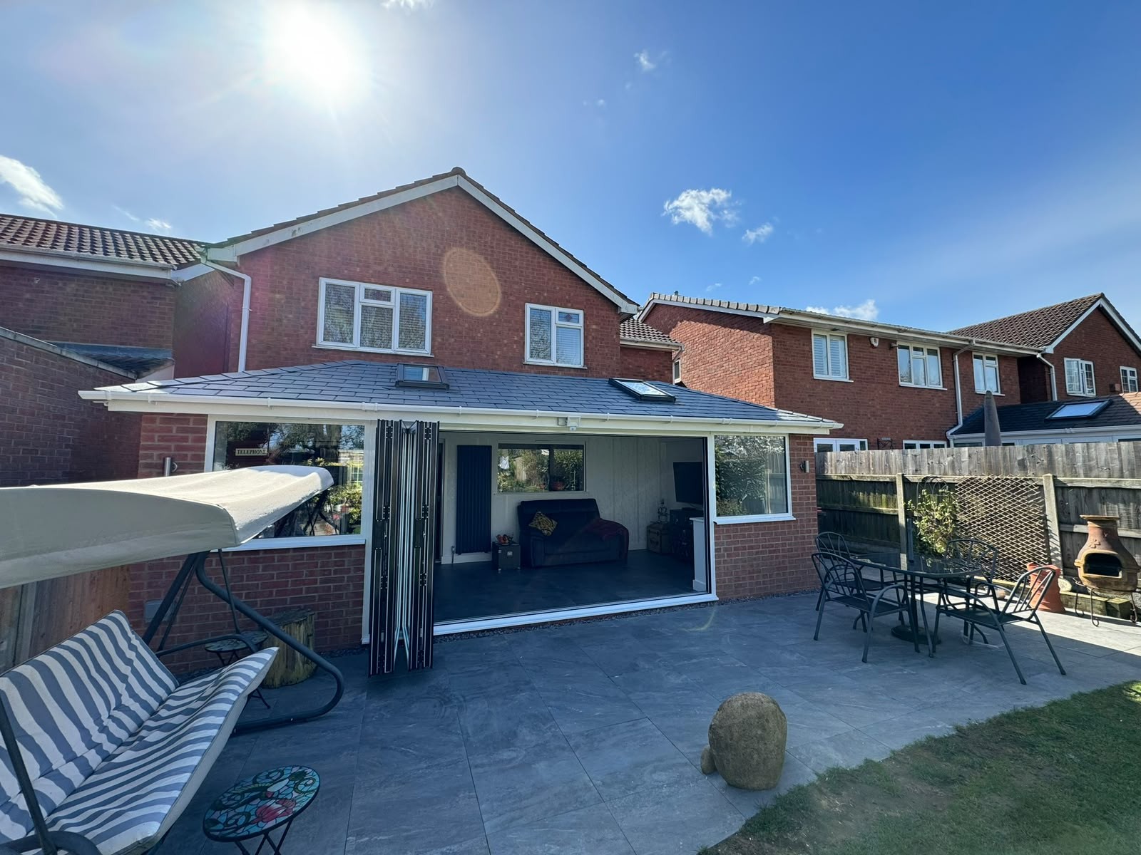 Warm roof conservatory with bi-fold doors open onto a patio