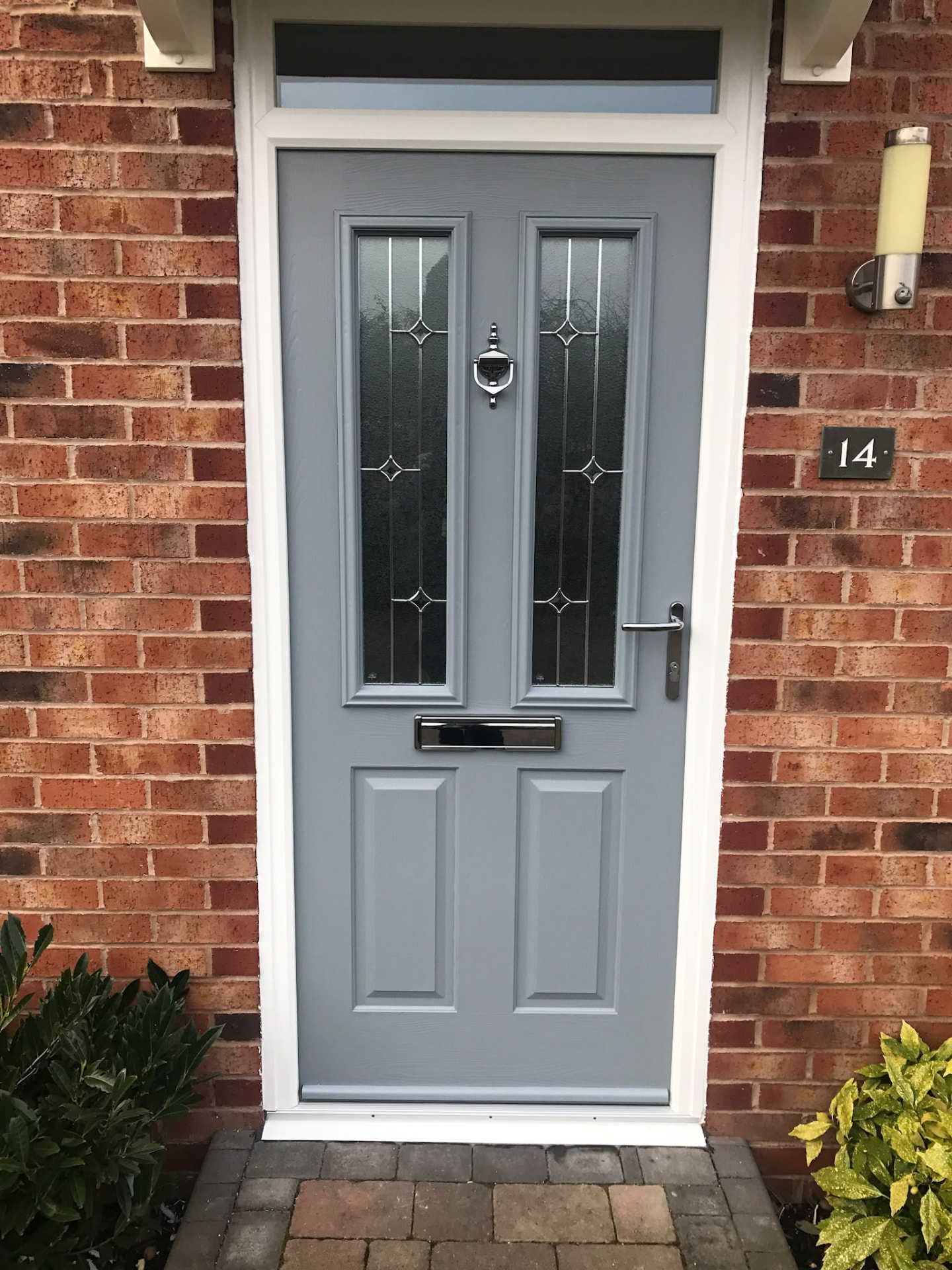 Grey four-panel composite front door with chrome furniture and glazed top light